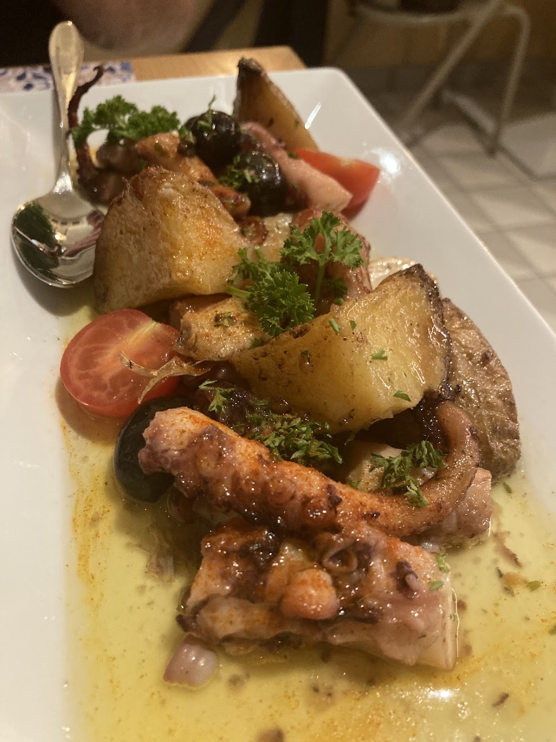 Gegrillter Oktopus mit Kartoffeln, Oliven und Kräutern bei warmem Abendlicht