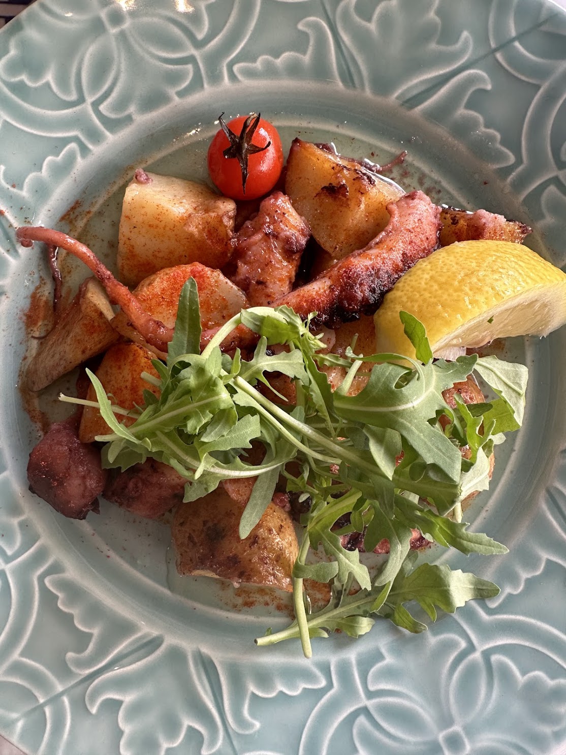 Oktopus mit Rucola, Kirschtomaten und Paprika auf geprägtem Teller